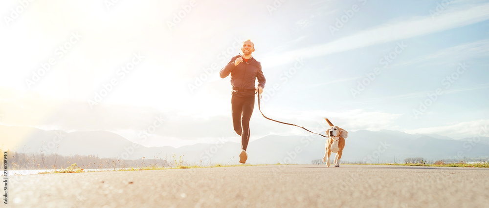 Jogging man with his dog in the morning. Active healthy lifestyle concept image. - obrazy, fototapety, plakaty 