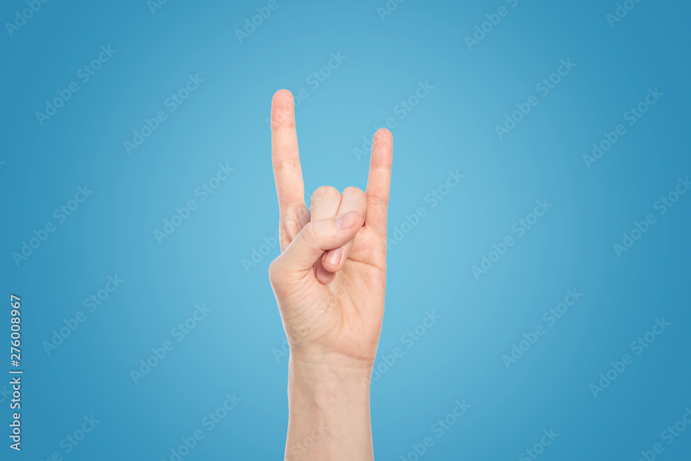 Hand show rock gesture on a blue background, close up. Hand show rock gesture on a blue background, close up.
