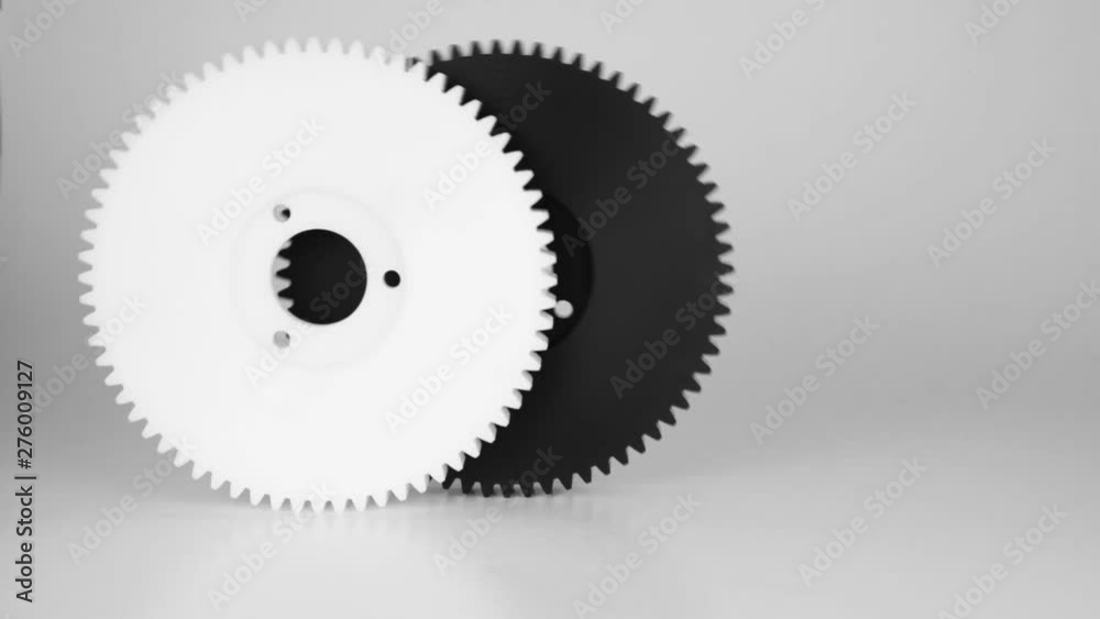 Rolling plastic gears in white and black, isolated on a white background. Rolling plastic gears in white and black, isolated on a white background.