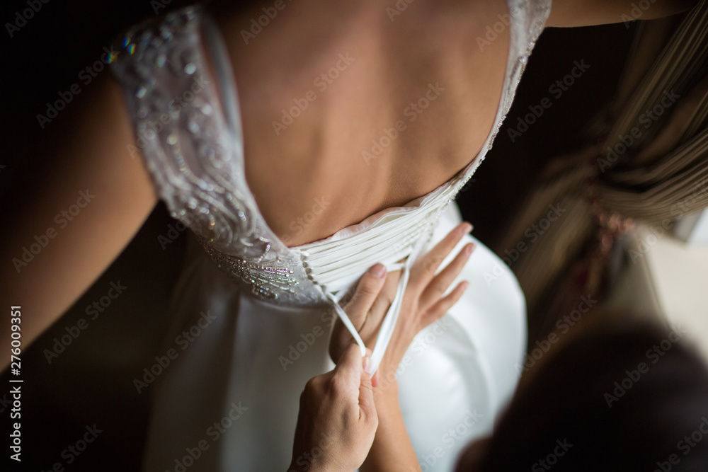 Naklejka premium Bride from the back. Lacing the wedding dress.