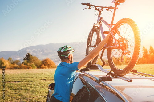 Mountain biker man take of his bike from the car roof