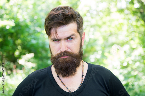 Beardy hipster. Brutal hipster on summer landscape. Bearded man in trendy hipster style outdoor. Caucasian hipster with thick beard hair and stylish haircut
