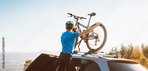 Mountain biker man take of his bike from the car roof