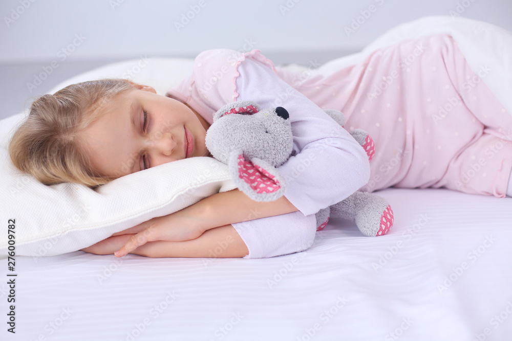 Child little girl sleeps in the bed with a toy teddy bear. Child little girl sleeps in the bed with a toy teddy bear.