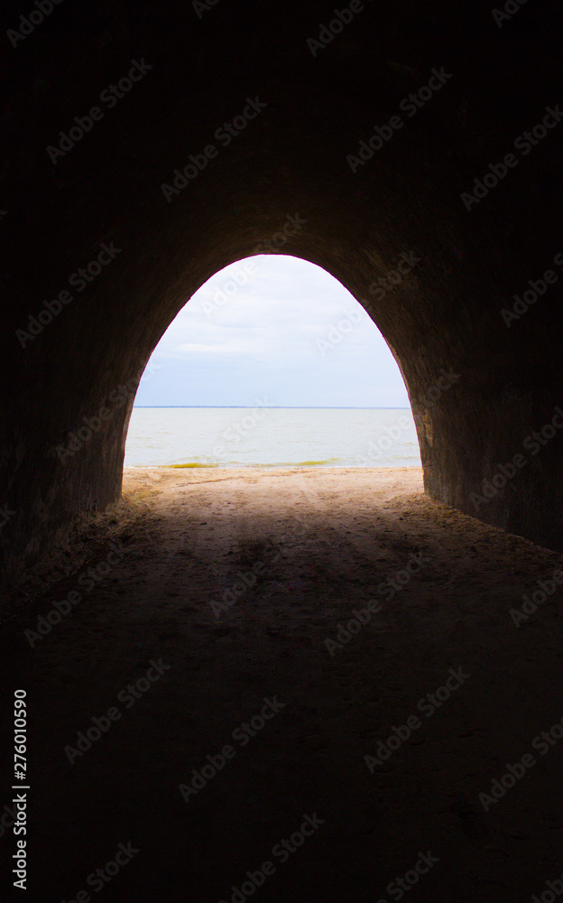 Light at the end of the tunnel. The outlines of the sea and the sandy shore appear.