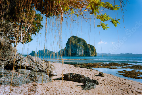 Philippines natural scenery beach at low tide, wooden bower at the tree, amazing Pinagbuyutan island in background. Exotic nature sea shore in El Nido, Palawan photo