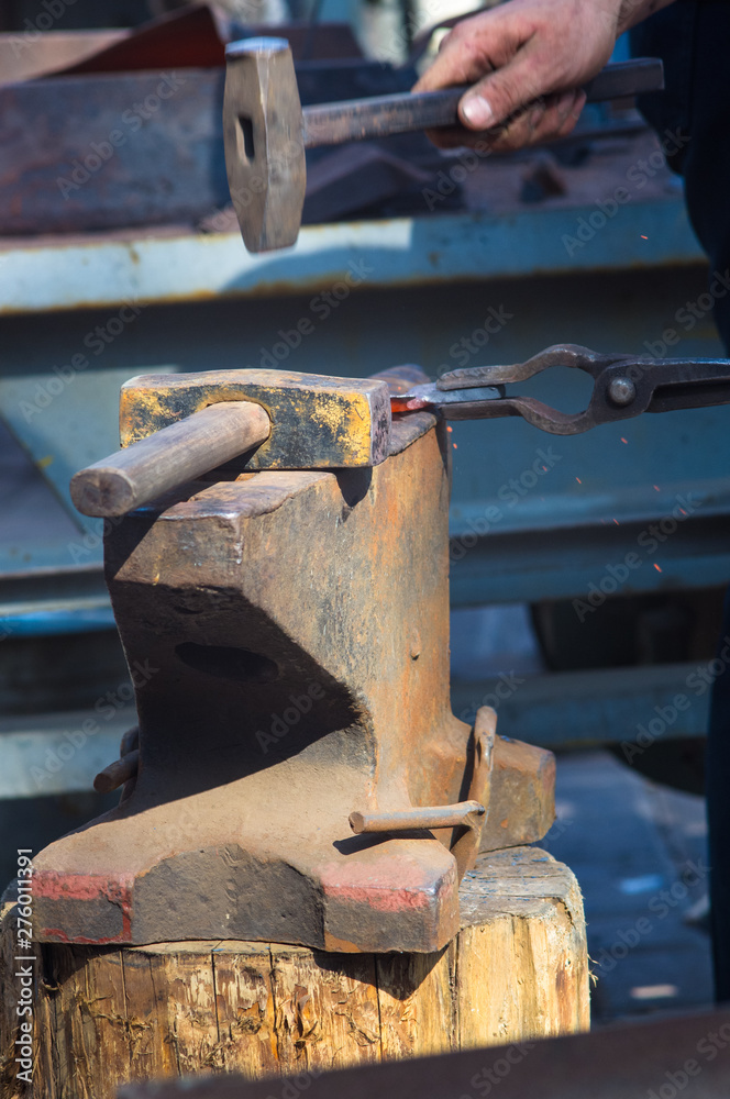 blacksmith performs the forging of hot glowing metal on the anvil blacksmith performs the forging of hot glowing metal on the anvil