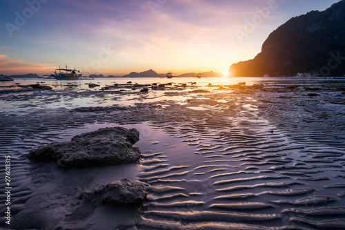 Tropical beach in ebb time low tide on sunset. Mudflats and sun reflections at the golden hour. mountain chain isles at horizon. Coron Corong beach, El Nido, Phillipines photo