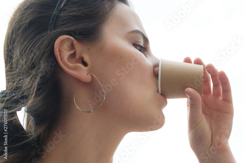 young woman drining espresso from disposable cup isolated on white background photo