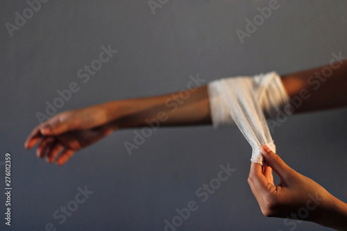 Woman putting a bandage on her arm.