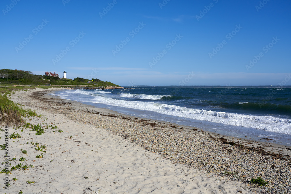 sandy beach and waves with Nobska Light lighthouse in the distance