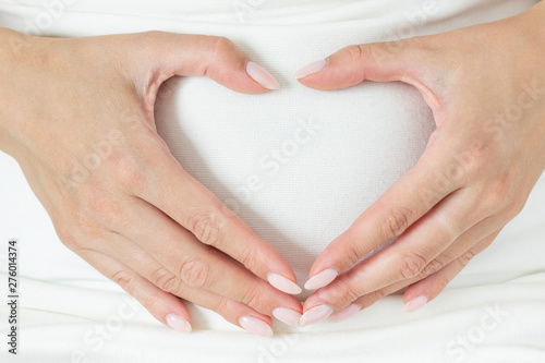 Woman holding her hands in a heart shape on her pregnant belly