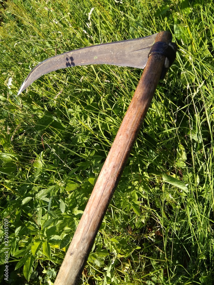 old scythe on background of green grass on a summer day, tool