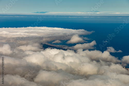 Panoramic view to Puerto de la Cruz and Orotava valley. Above wight fluffy clouds  clear blue sky and small part of La Palma island in the line of horizon. Spain  Canary Islands  Tenerife