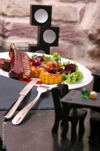 Grilled lamb ribs served with grilled corn, salat, bbq sauce, on a white plate. Food photo for restaurant menu.