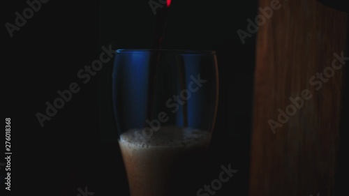 Dark frothy beer poured into a glass closeup