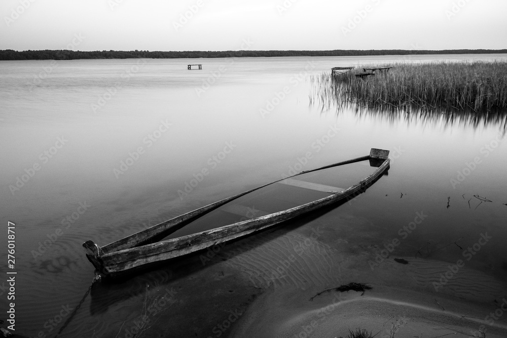 Naklejka premium A canoe on the shore of the lake. A moody landscape. Liutsymer Lake. Polesie. Ukraine
