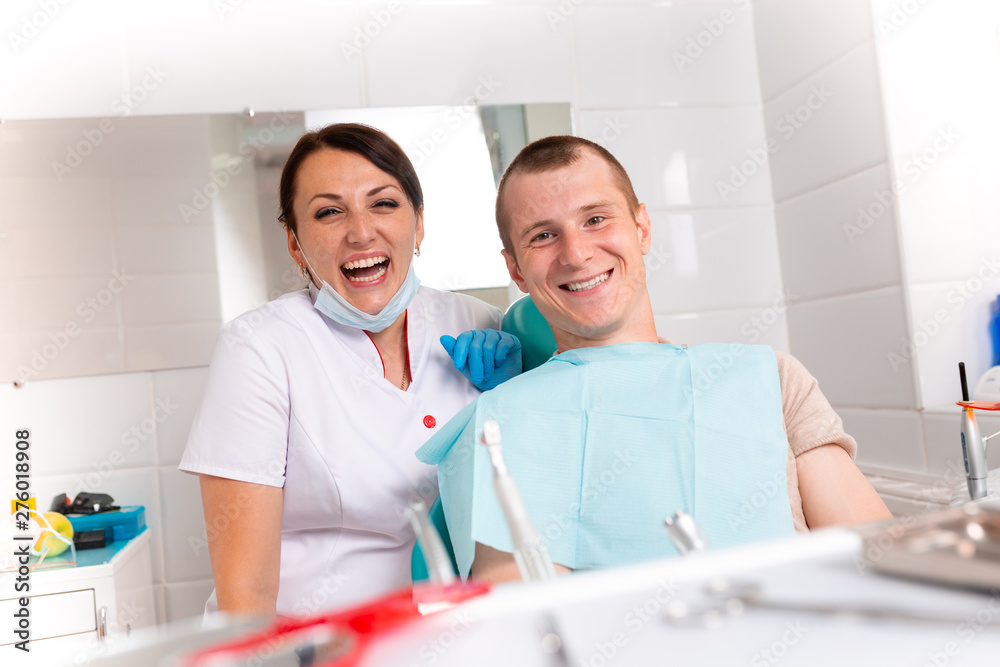 The dentist and her happy patient look at the camera and smile. Reception at the dentist, healthy teeth, happy patient, beautiful teeth. The dentist and her happy patient look at the camera and smile. Reception at the dentist, healthy teeth, happy patient, beautiful teeth.