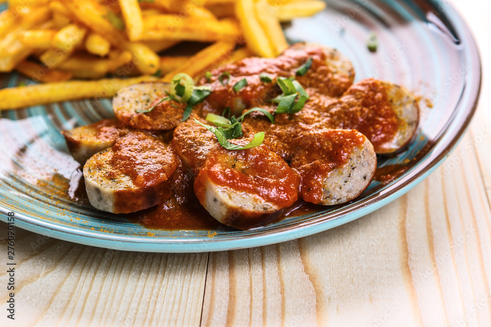 Fried sausages with French fries sprinkled with green onions. A fragment of a dish close-up Fried sausages with French fries sprinkled with green onions. A fragment of a dish close-up