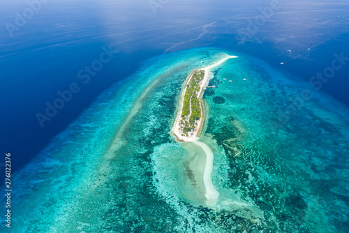 Aerial view of a tiny, tropical island surrounded by large, fringing tropical coral reef