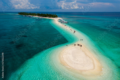 Aerial drone view of people and bangka boats on a tiny, tropical sandspit and coral reef photo