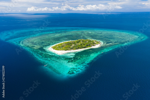Aerial drone view of a beautiful tropical island surrounded by coral reef and deep ocean (Mantigue Island)