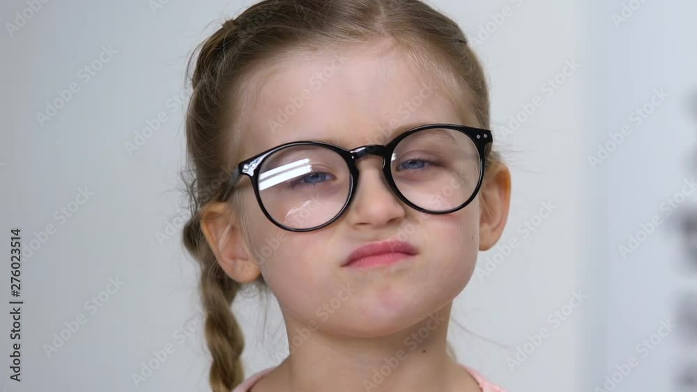 Male ophthalmologist giving eyeglasses to small farsighted girl, health care Male ophthalmologist giving eyeglasses to small farsighted girl, health care