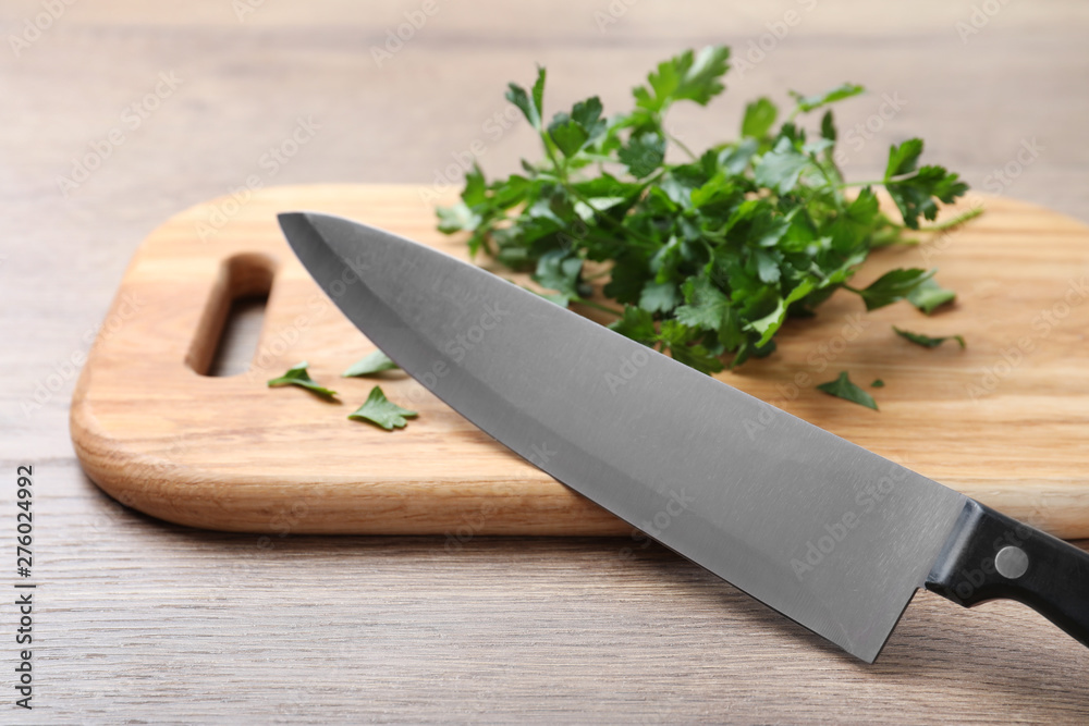 Cutting board with chef's knife and fresh parsley on wooden table Cutting board with chef's knife and fresh parsley on wooden table