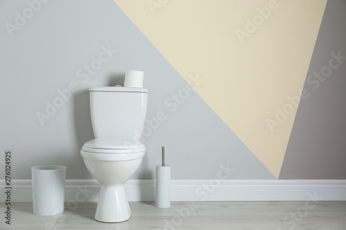 Simple bathroom interior with new toilet bowl near color wall. Space for text