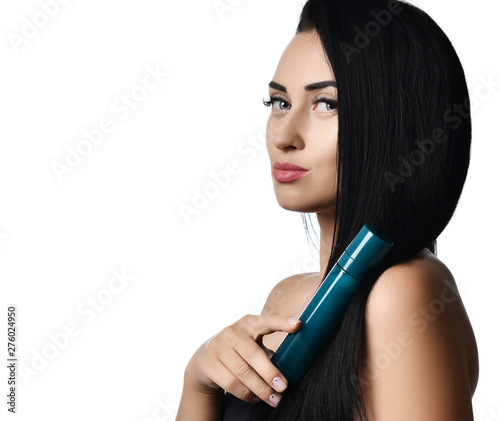 Brunette woman in profile leaned a bottle of perfume cosmetic to her long straight hair on white. Advertisement concept 