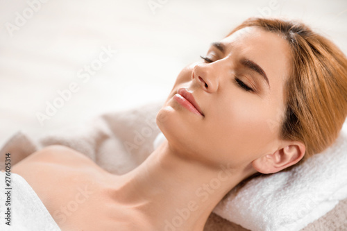 Beautiful woman with silky skin after face mask relaxing in spa salon