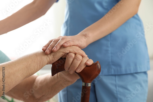 Nurse assisting elderly woman with cane, closeup © New Africa