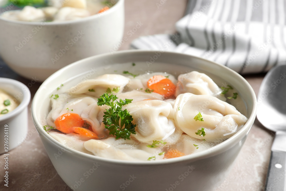 Bowl of tasty dumplings in broth on table, closeup Bowl of tasty dumplings in broth on table, closeup