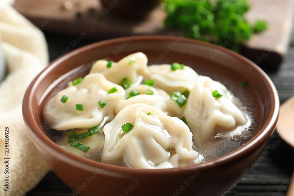 Bowl of tasty dumplings in broth on table, closeup Bowl of tasty dumplings in broth on table, closeup