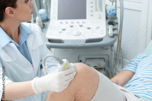 Doctor conducting ultrasound examination of patient s knee in clinic