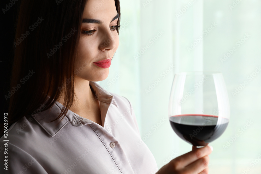 Beautiful young woman with glass of luxury red wine indoors. Space for text Beautiful young woman with glass of luxury red wine indoors. Space for text