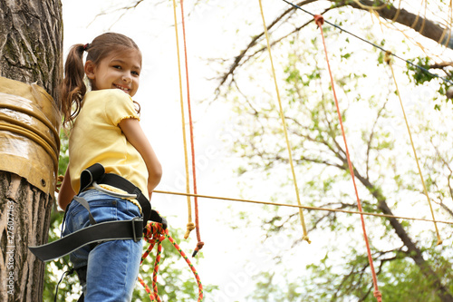 Little girl climbing in adventure park, space for text. Summer camp