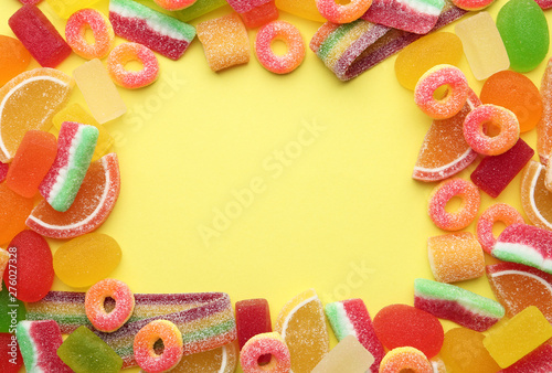 Frame made with tasty jelly candies on color background, top view. Space for text