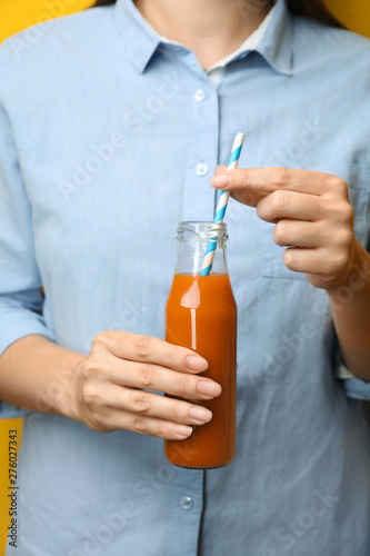Woman holding bottle of tasty carrot juice, closeup