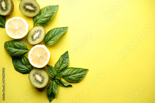Tropical background, summertime, vacation, refreshment concept. Fruits rich in vitamins, kiwi and lemon slices on bright yellow table