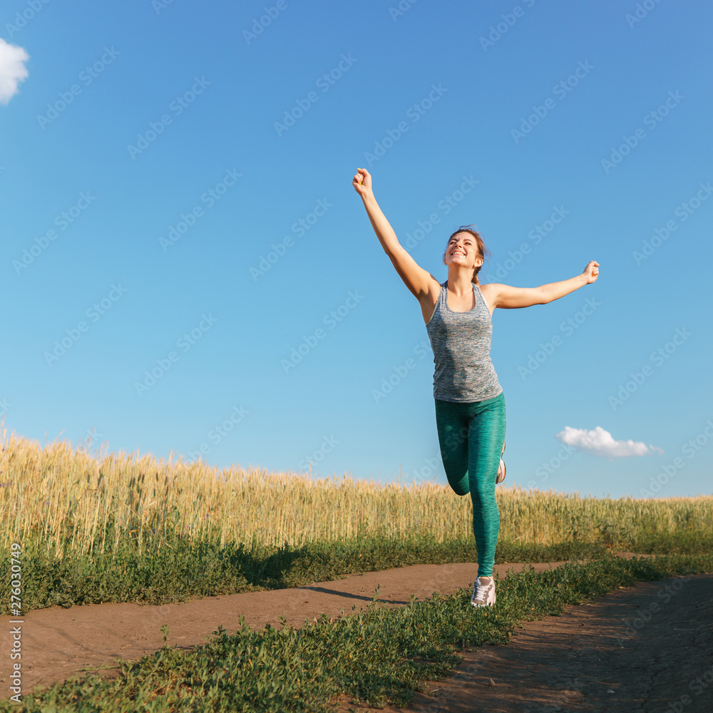 Happy woman on sunset or sunrise. Female runner raising arms expressing positivity and success. Winner, happiness concept