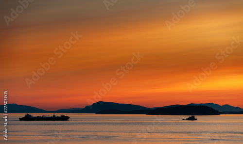 Tugboat and Barge Motoring Through the Puget Sound.. With the islands Matia and Sucia in the background a tugboat makes it's way through the Salish Sea in northwest Washington State. photo