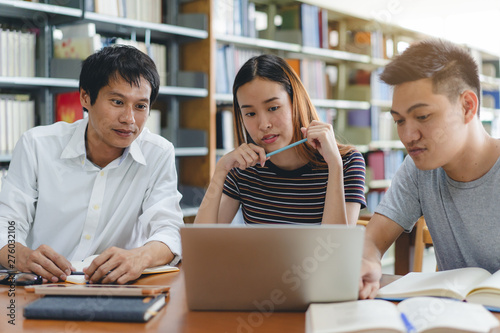 Group of asian students researching for project in library of university.