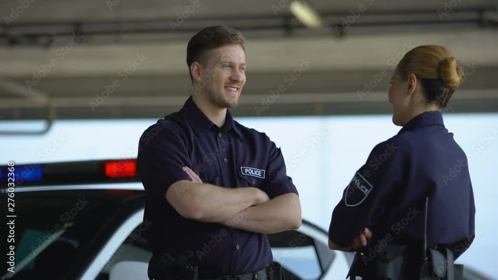 Male and female police officers giving high five, satisfied with good job, duty Male and female police officers giving high five, satisfied with good job, duty