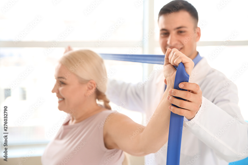 Fototapeta premium Physiotherapist working with mature patient in rehabilitation center