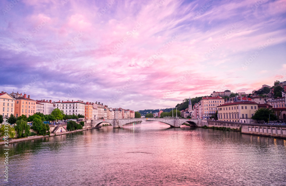 Obraz premium A view of Lyon, France along the Saône river at sunset.