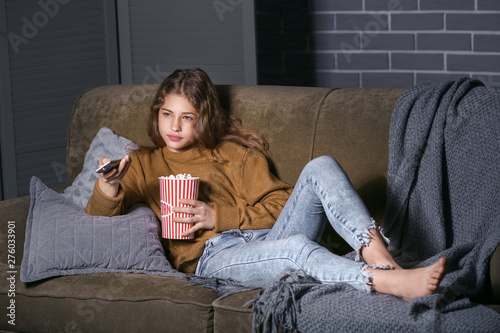 Teenage girl watching TV at...