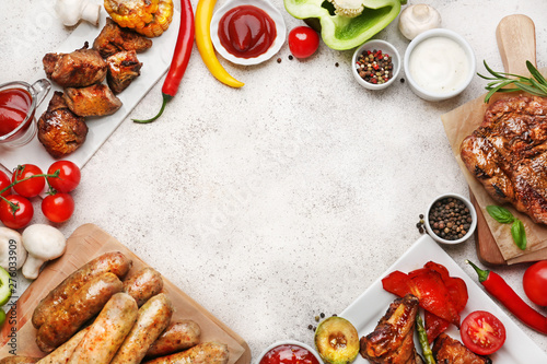Frame made of tasty grilled meat with sausages and vegetables on light background
