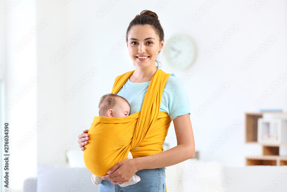 Young mother with little baby in sling at home - obrazy, fototapety, plakaty 