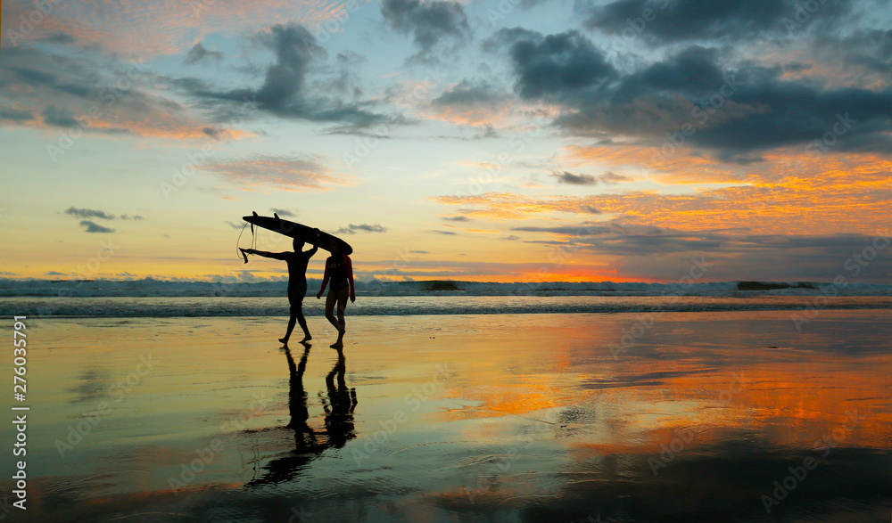 sunset with the silhouette of surfer on the beach in bali sunset with the silhouette of surfer on the beach in bali